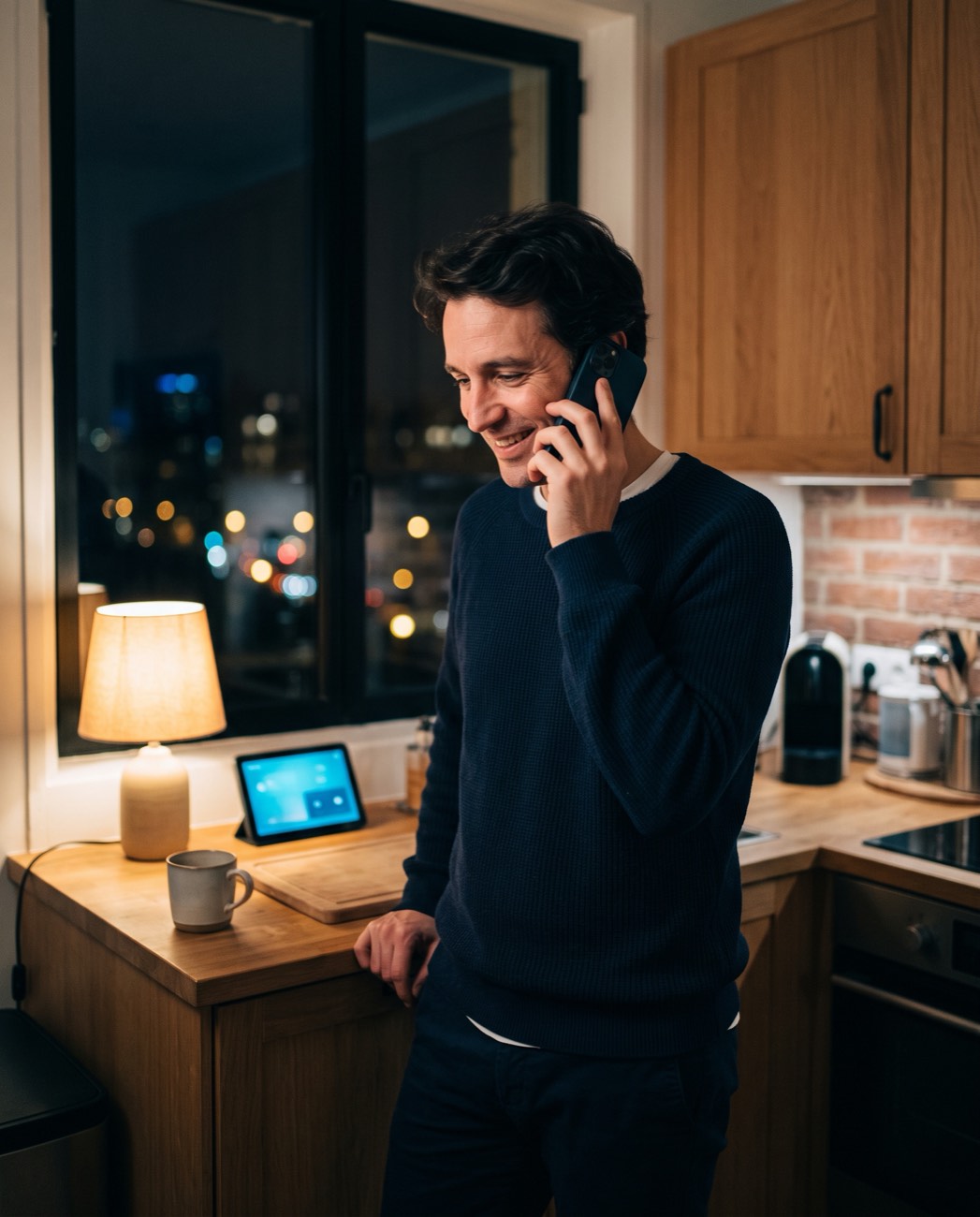 Un homme chez lui, le soir, téléphone au cabinet et sourit.